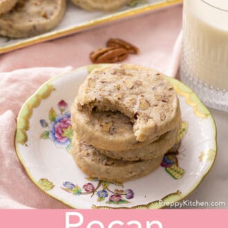 pecan sandies stacked on a floral plate with a glass of milk
