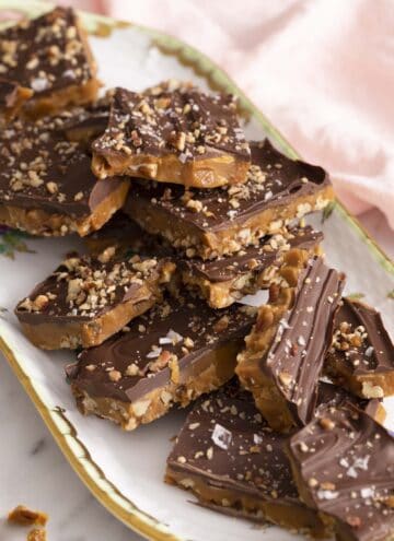 Toffee pieces topped with chocolate on a tray.