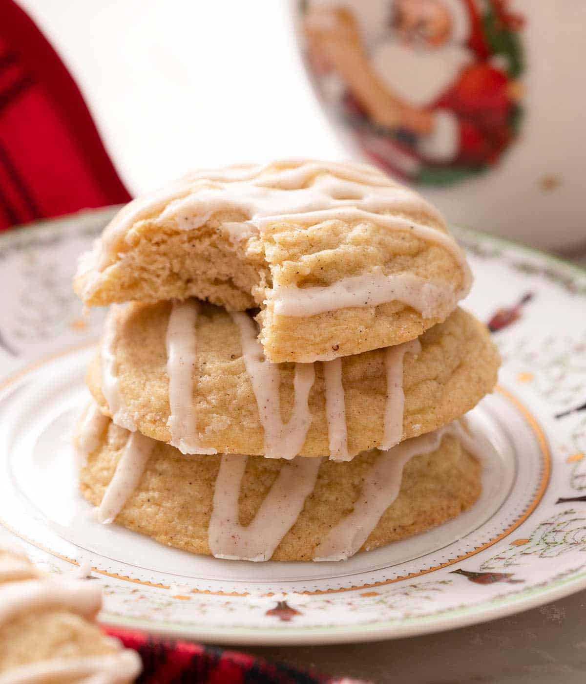A photo of eggnog cookies stacked on top of each other and one with a bite out