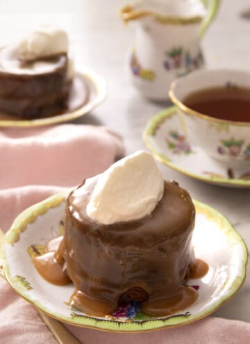 A sticky toffee pudding on a plate with a dollop of whipped cream on top