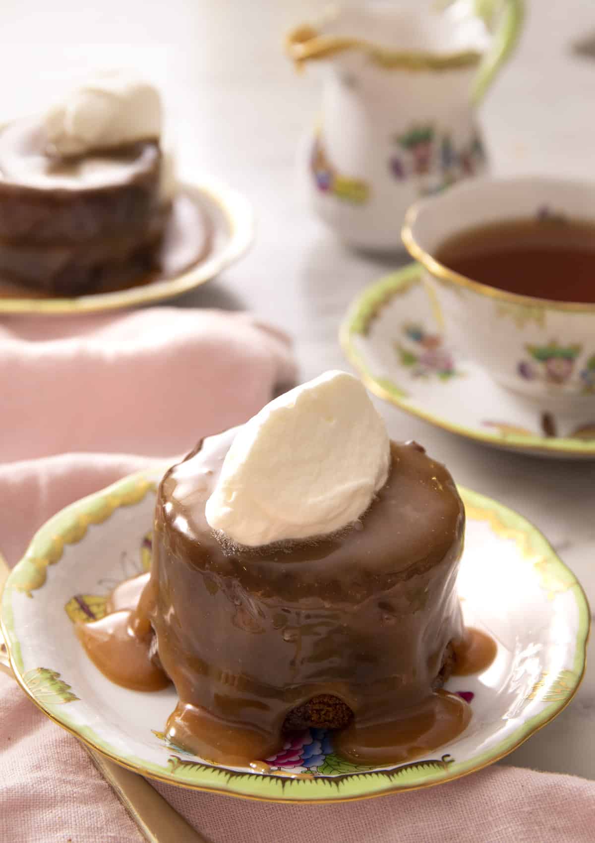 A sticky toffee pudding on a plate with a dollop of whipped cream on top