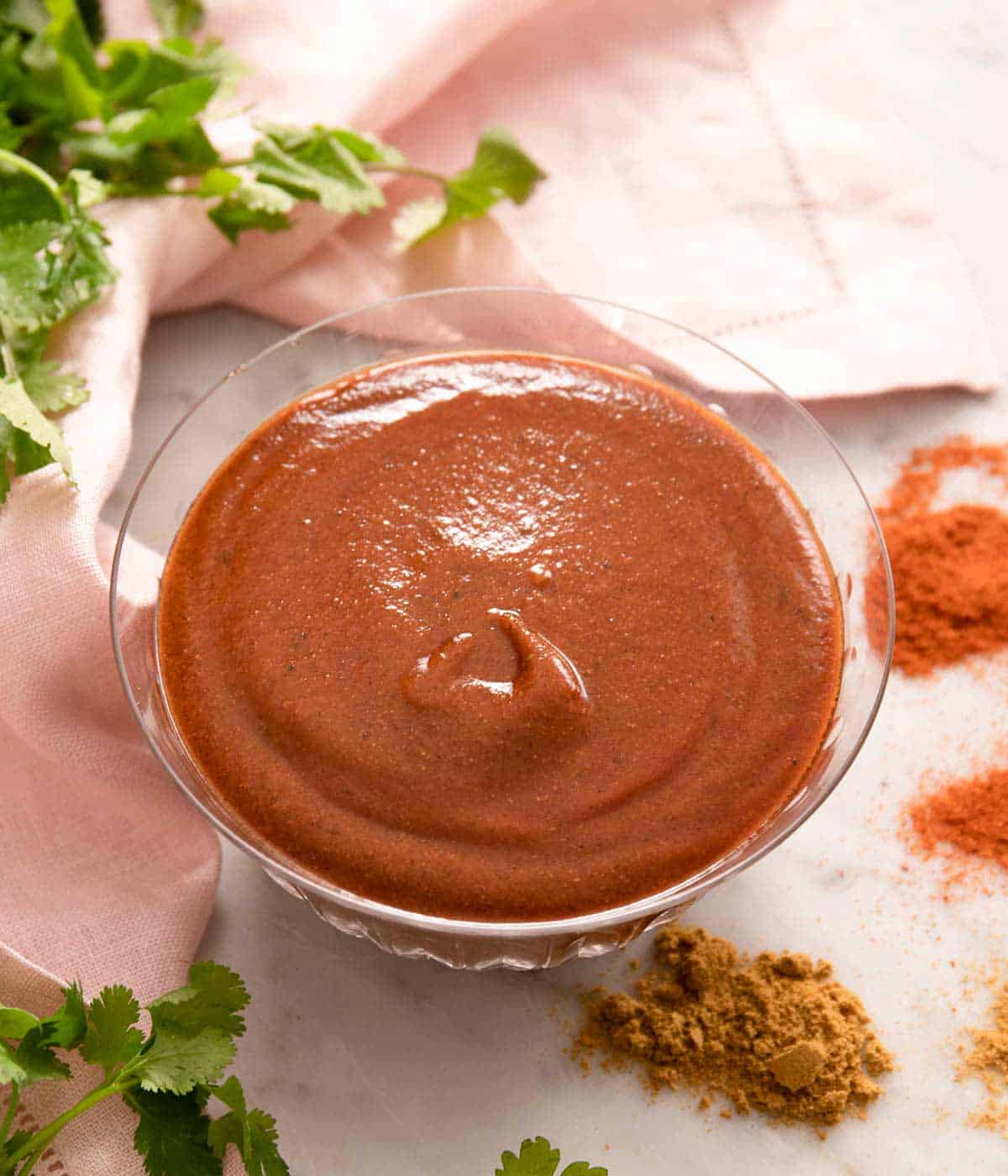 A bowl of enchilada sauce on a white surface