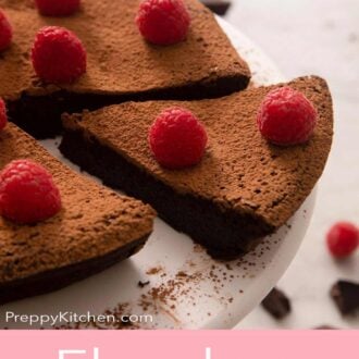 A pinterest graphic of a flourless chocolate cake with a slice cut and pulled out. Raspberries on top.