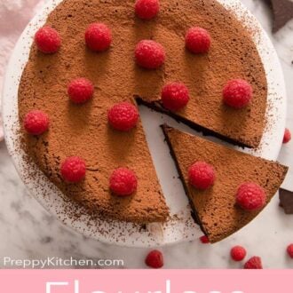 A pinterest graphic of a flourless chocolate cake topped with raspberries with a slice cut and pulled out.