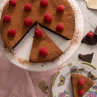 A pinterest graphic of an overhead view of a flourless chocolate cake with slices cut out and one slice plated.