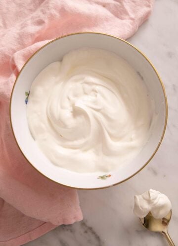 Sour cream in a bowl with a gold spoon beside it.