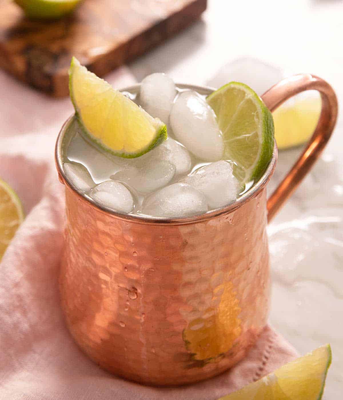 A close up of a Moscow Mule cocktail topped with lime wedges