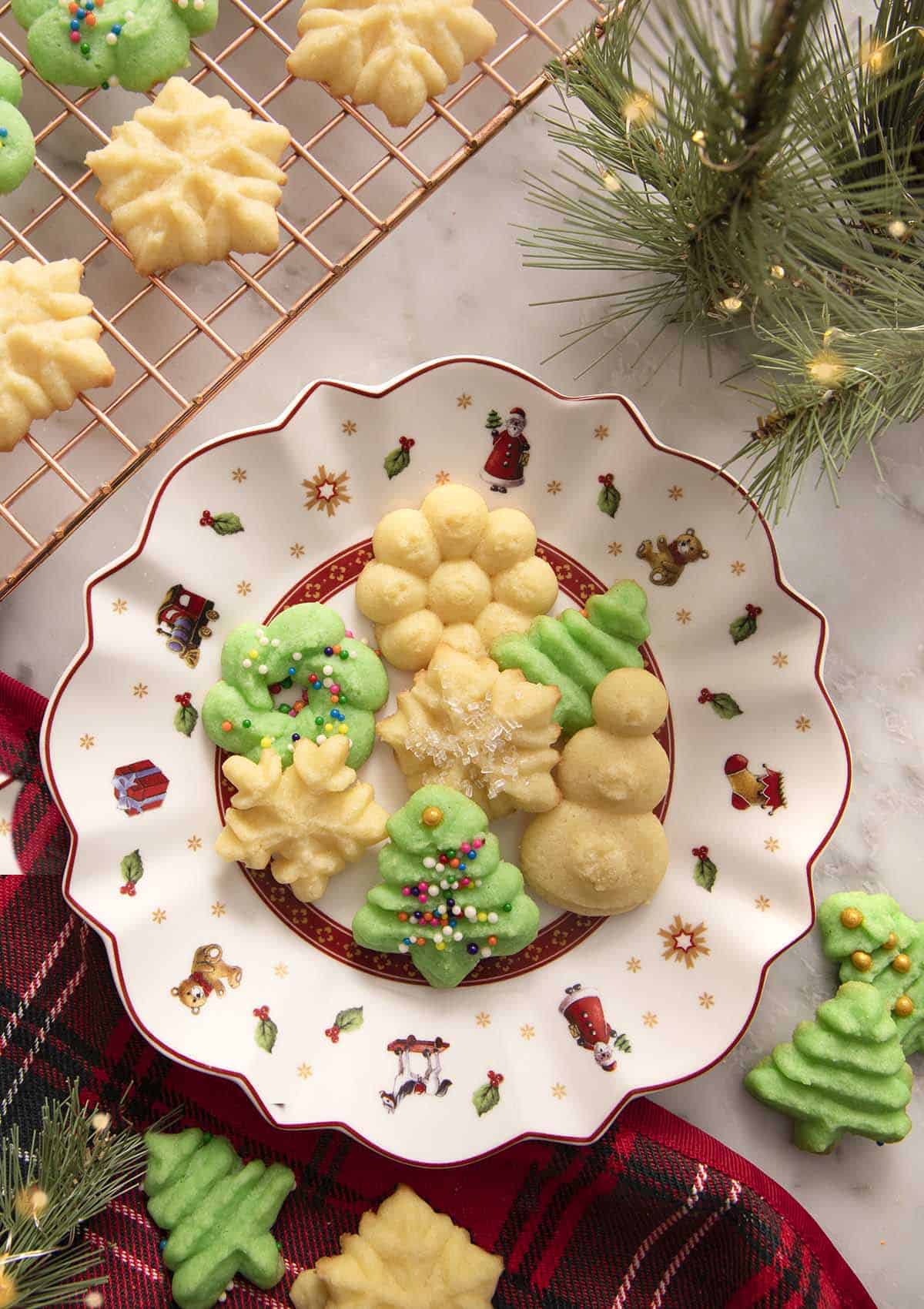 A white and red Christmas plate filled with green and white Christmas cookies.