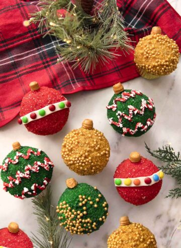 A group of cupcakes decorated as colorful Christmas ornaments.