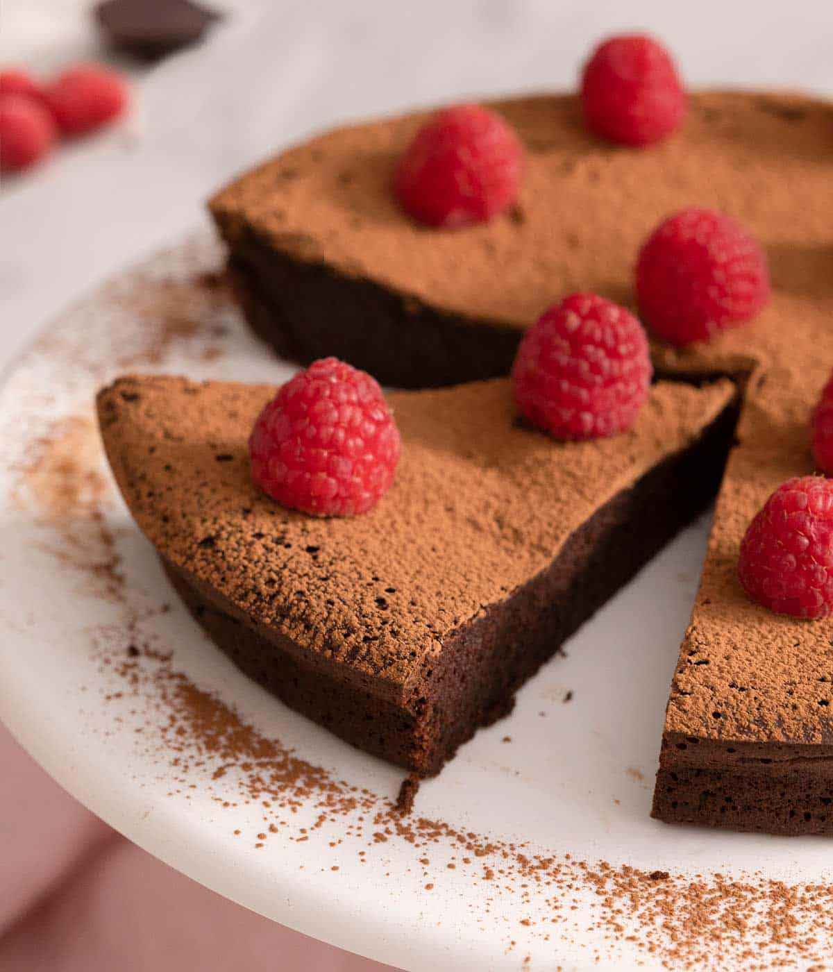 A close up of a slice of chocolate cake topped with raspberries.