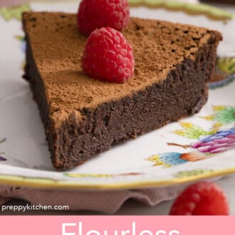 A piece of a slice of flourless chocolate cake topped with raspberries.