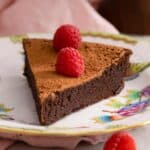 A close up of a slice of flourless chocolate cake on a plate.