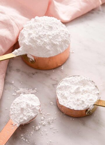 Powdered sugar in measuring cups and a measuring spoon