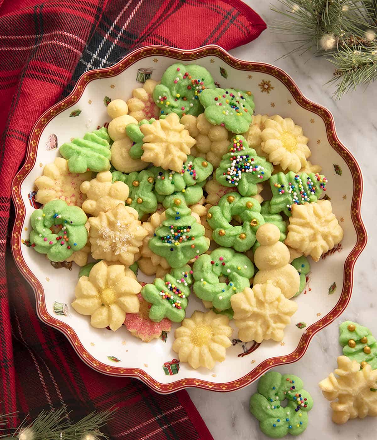 A large red and white serving bowl filled with spritz cookies made with various patterns.