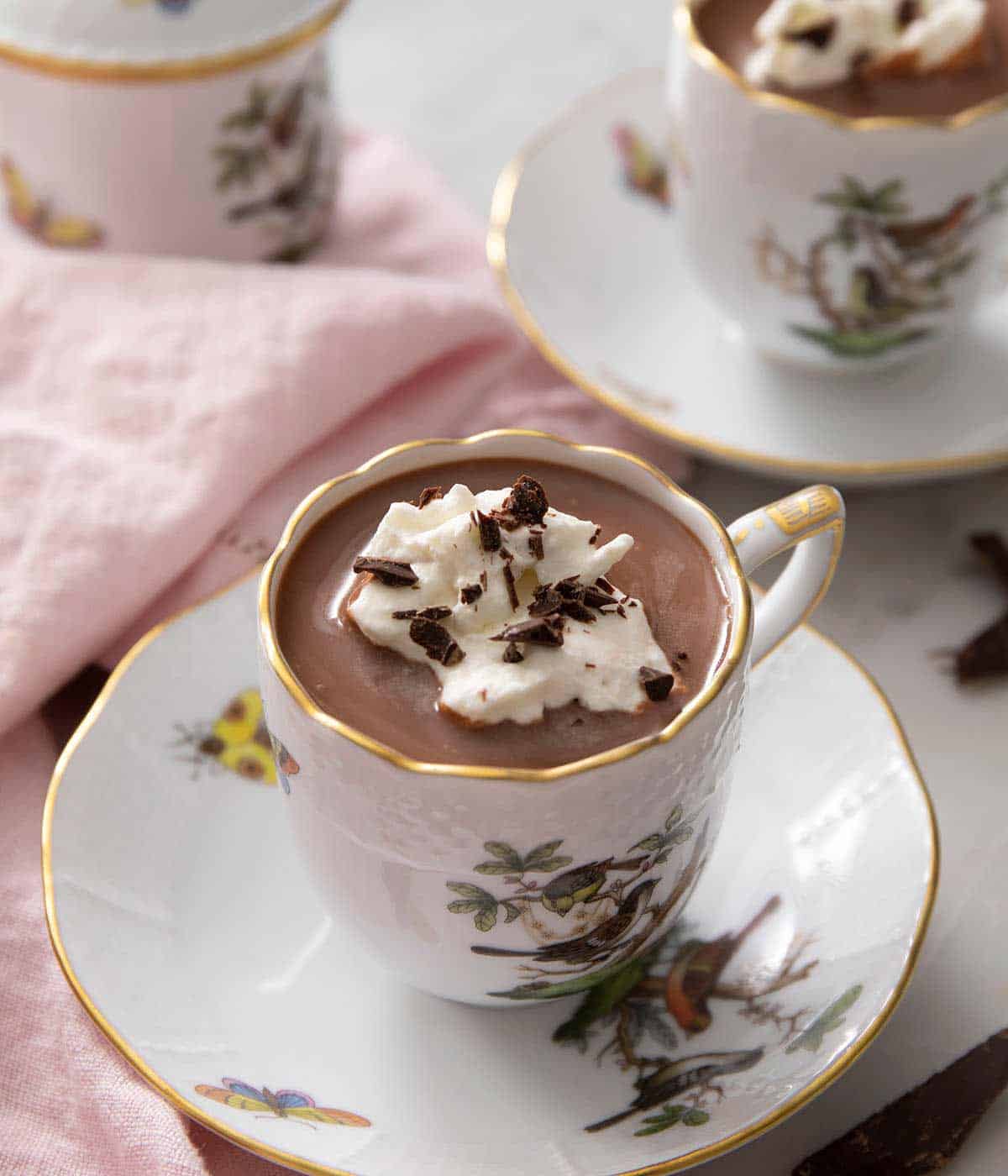 A side shot of a mug of hot chocolate topped with whipped cream.