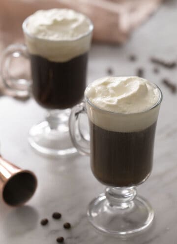 Two Irish coffees topped with whipped cream