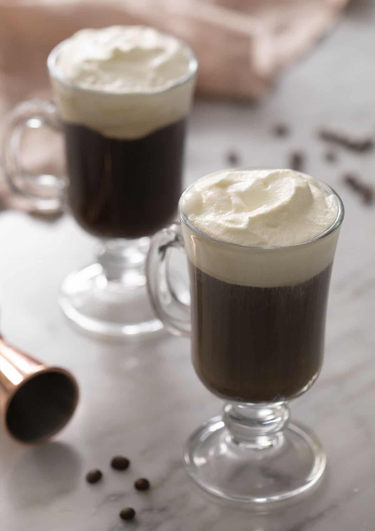 Two Irish coffees topped with whipped cream