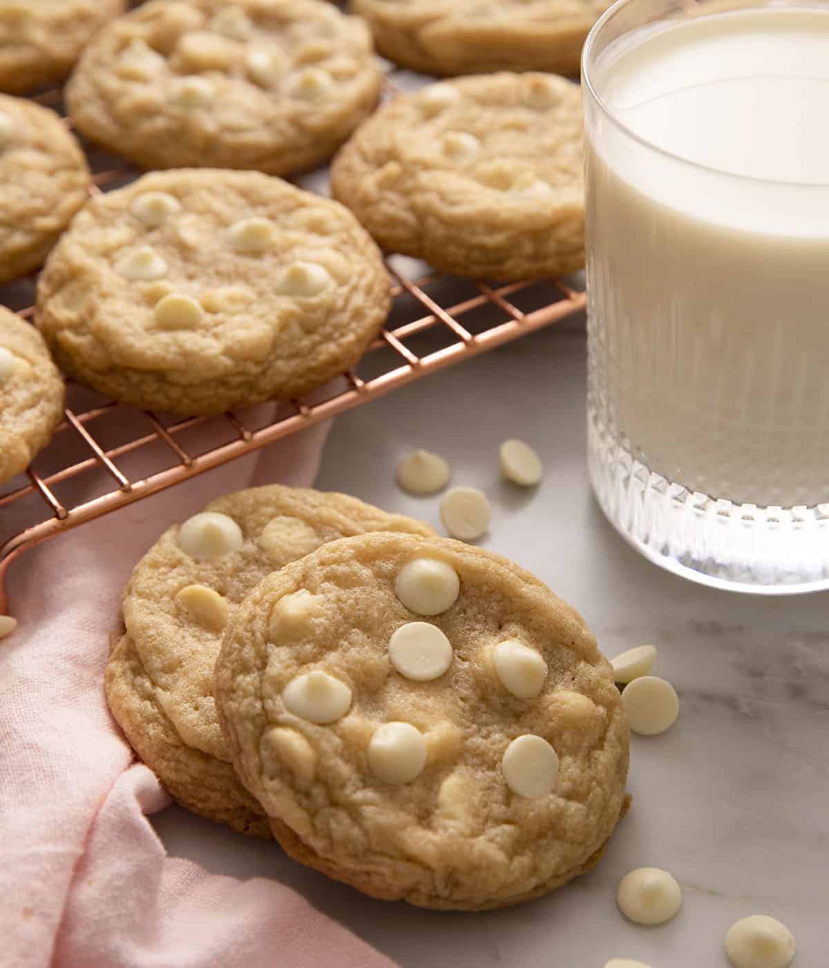 A close up of two cookies beside a glass of milk