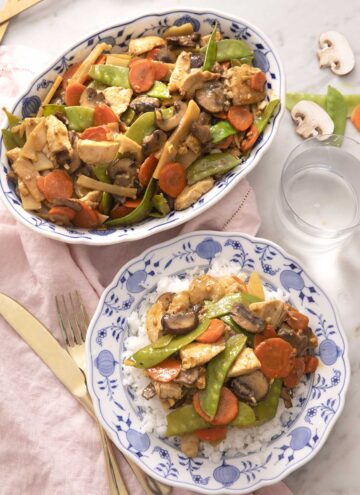 An overhead shot of moo goo gai pan in a platter and some served over a plate of rice.
