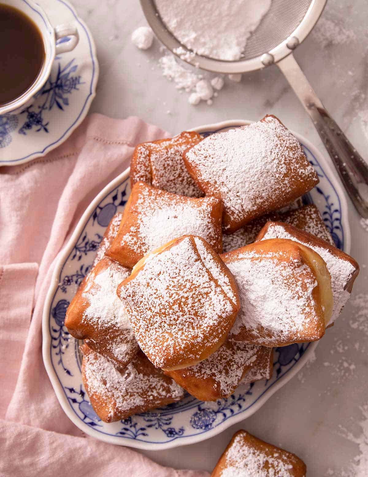 A pile of beignets on a blue serving plate.