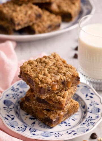 A stack of three carmelitas on a blue and white plate. A glass of milk on the side.