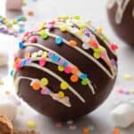 A close up of a hot chocolate bomb topped with sprinkles