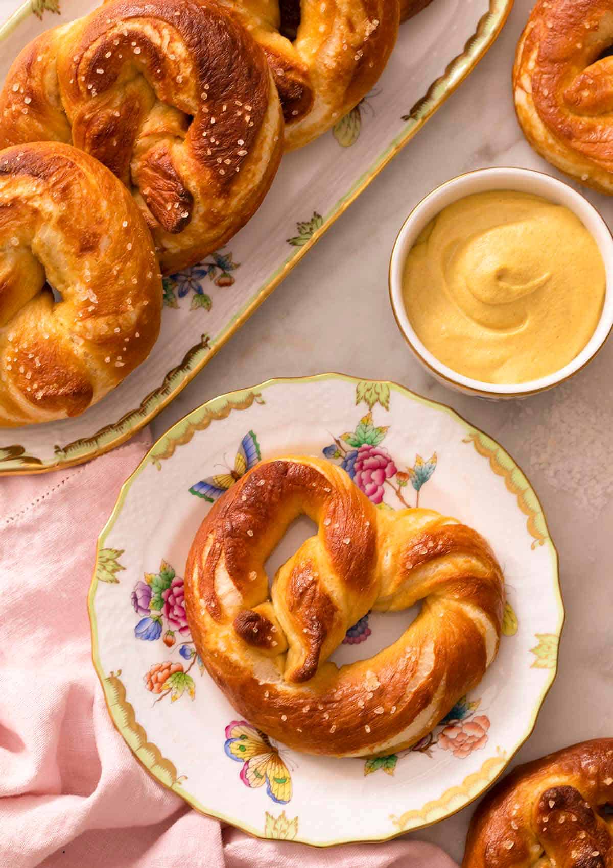 An overhead shot of a soft pretzel on a plate next to mustard