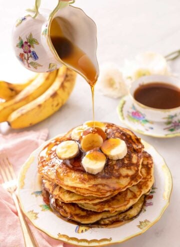 A jug powring syrup of banana pancakes