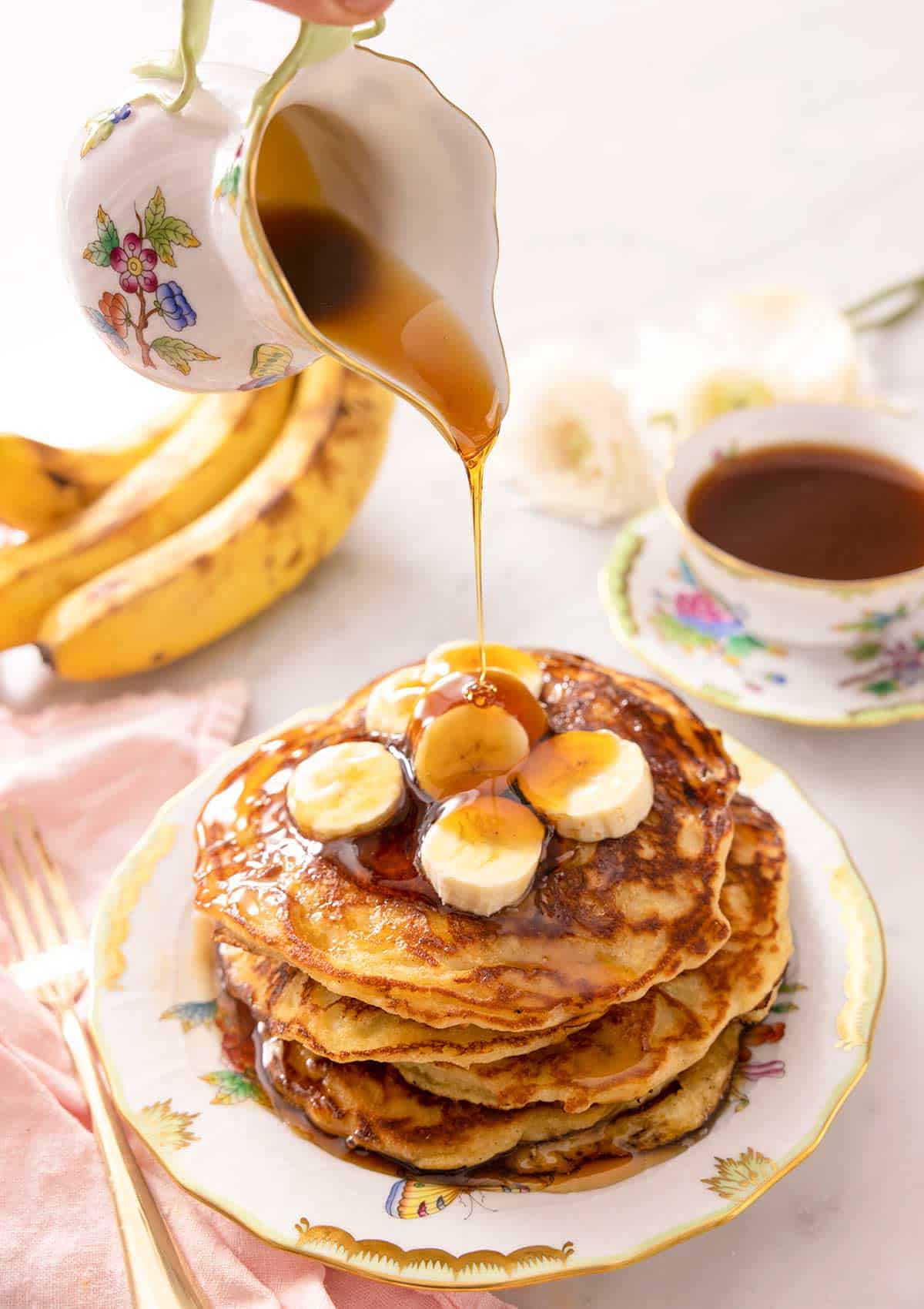 A jug powring syrup of banana pancakes