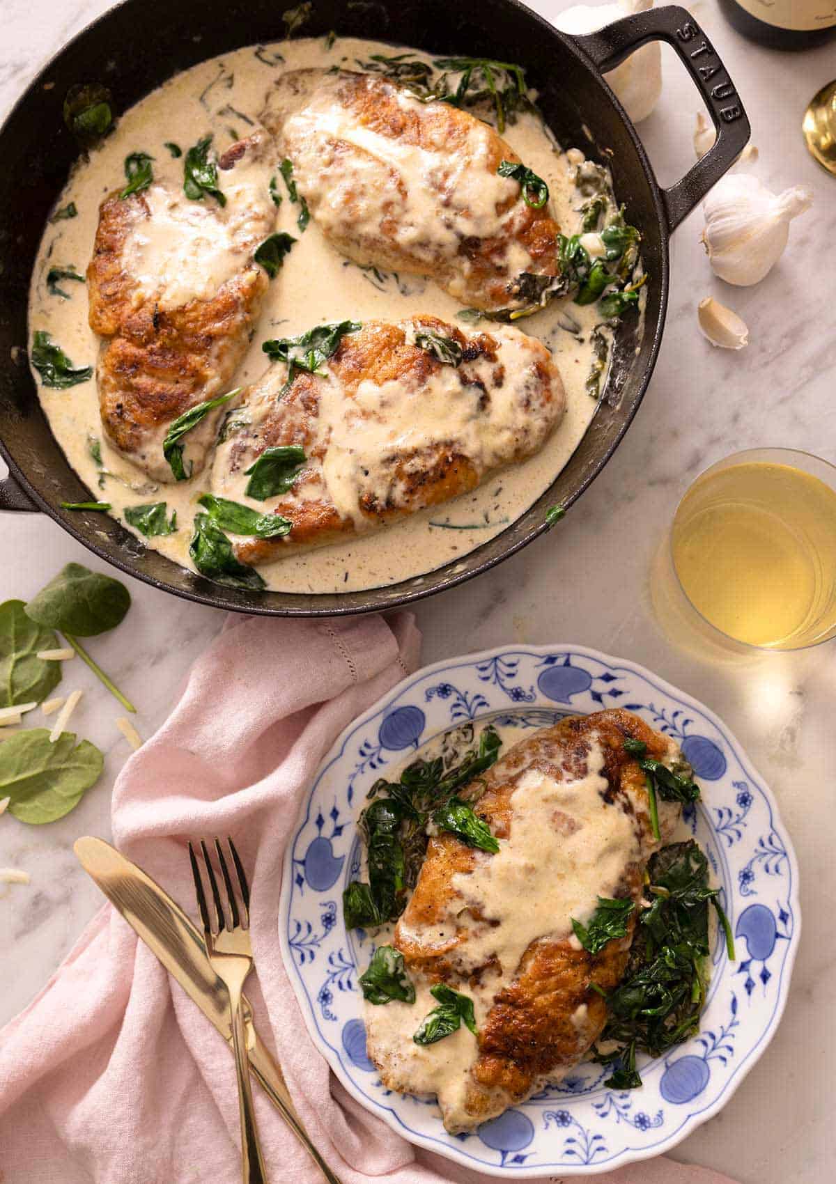 Overhead view of a braiser containing chicken florentine with a serving plated up beside it.