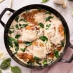 Overhead view of chicken florentine in a large cast iron pot, with the chicken coated in the sauce.