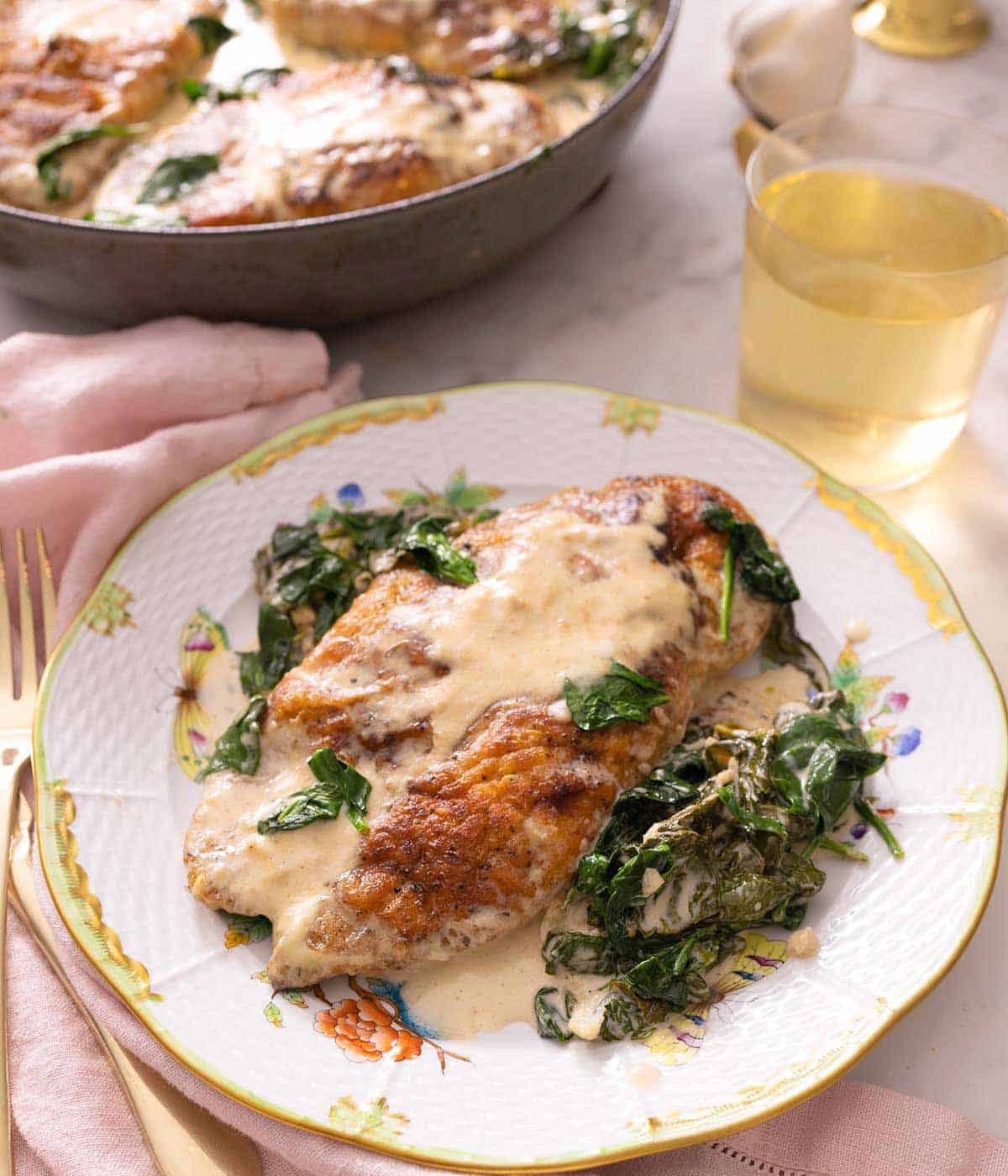 A plate of chicken florentine with the chicken breast coated in sauce and spinach.
