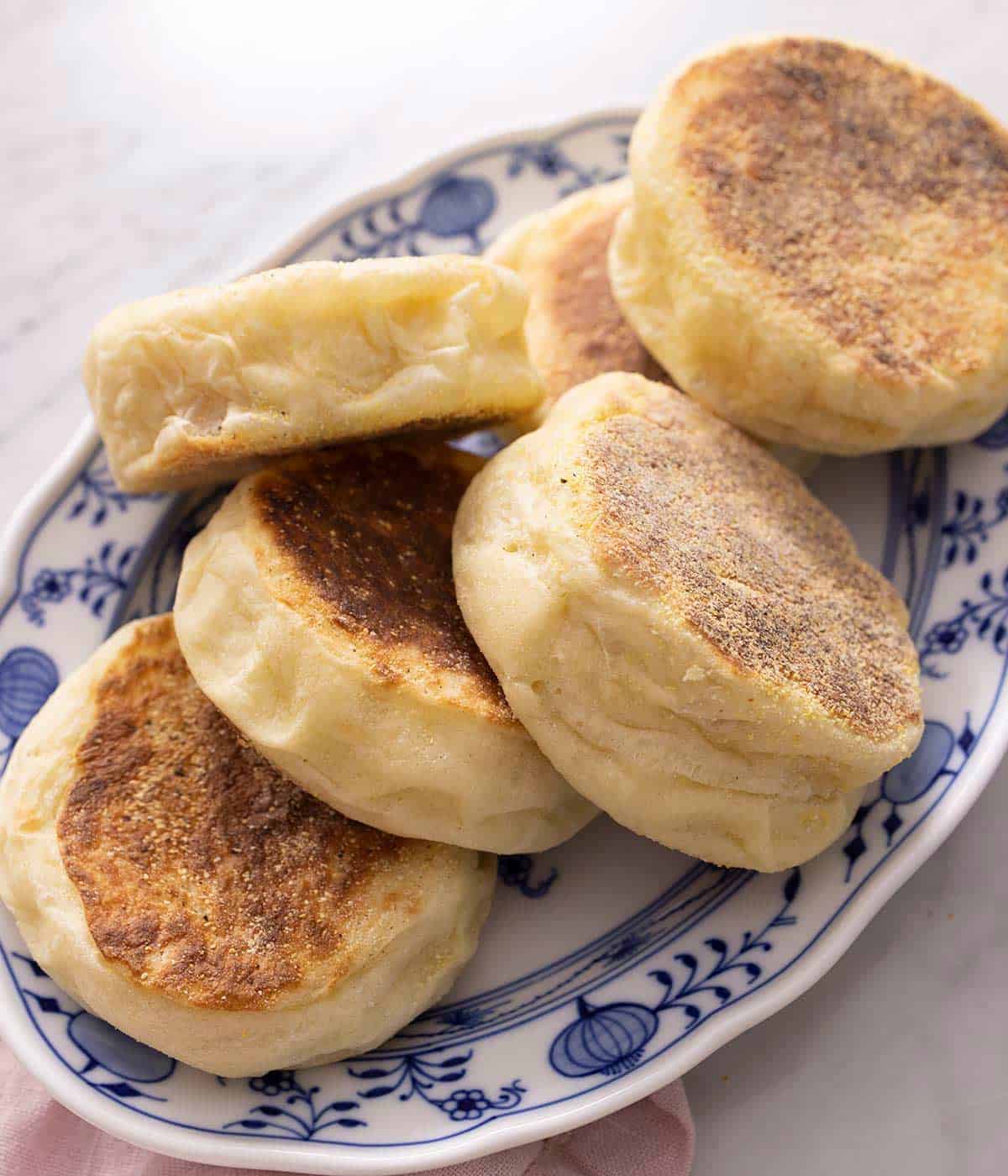 A pile of English Muffins on a blue serving plate.