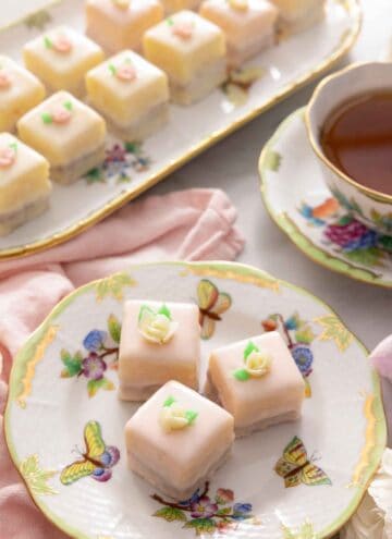 Overhead view of a serving platter of petit fours beside a plate with three.
