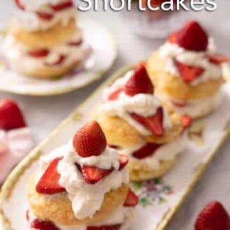 Pinterest graphic of a platter of three strawberry shortcakes topped with cream and sliced strawberries.