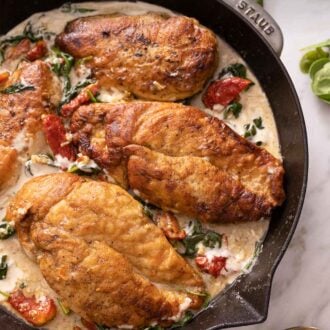 Pinterest graphic of a Staub pan with four chicken breasts in a creamy Tuscan sauce.