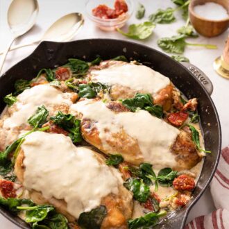 Pinterest graphic of a pan of creamy Tuscan chicken with spinach and sun dried tomatoes.