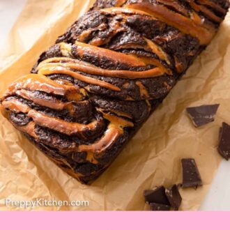 Pinterest graphic of an overhead view of a loaf of babka on a sheet of brown parchment with roughly chopped chocolate beside it.