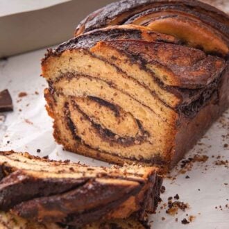 Pinterest graphic of a cut loaf of babka, showing the swirls of chocolate inside of the bread.