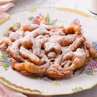 Funnel cake on a plate with powdered sugar on top.