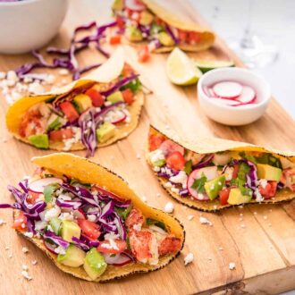 Pinterest graphic of a cutting board with four lobster tacos with small bowls of toppings on the board.