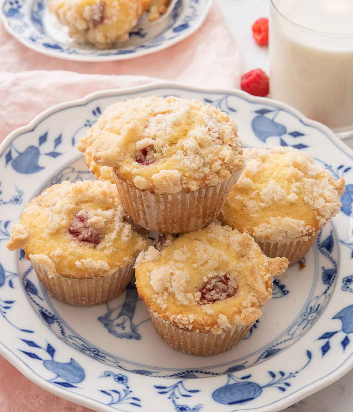 A stack of five raspberry muffins on a white and blue plate.