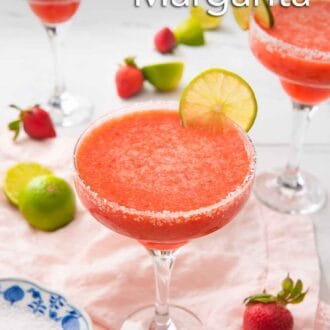 Pinterest graphic of three strawberry margaritas with a slice of lime as garnish with more strawberries and cut limes on the countertop.