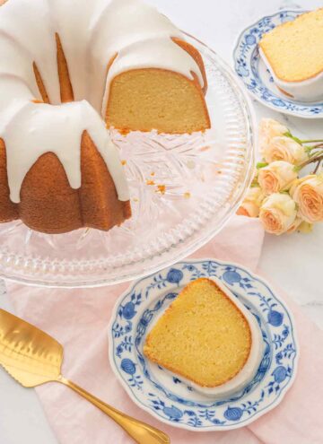 Overhead view of a vanilla Bundt cake with two slices cut out on their own small dessert plates.