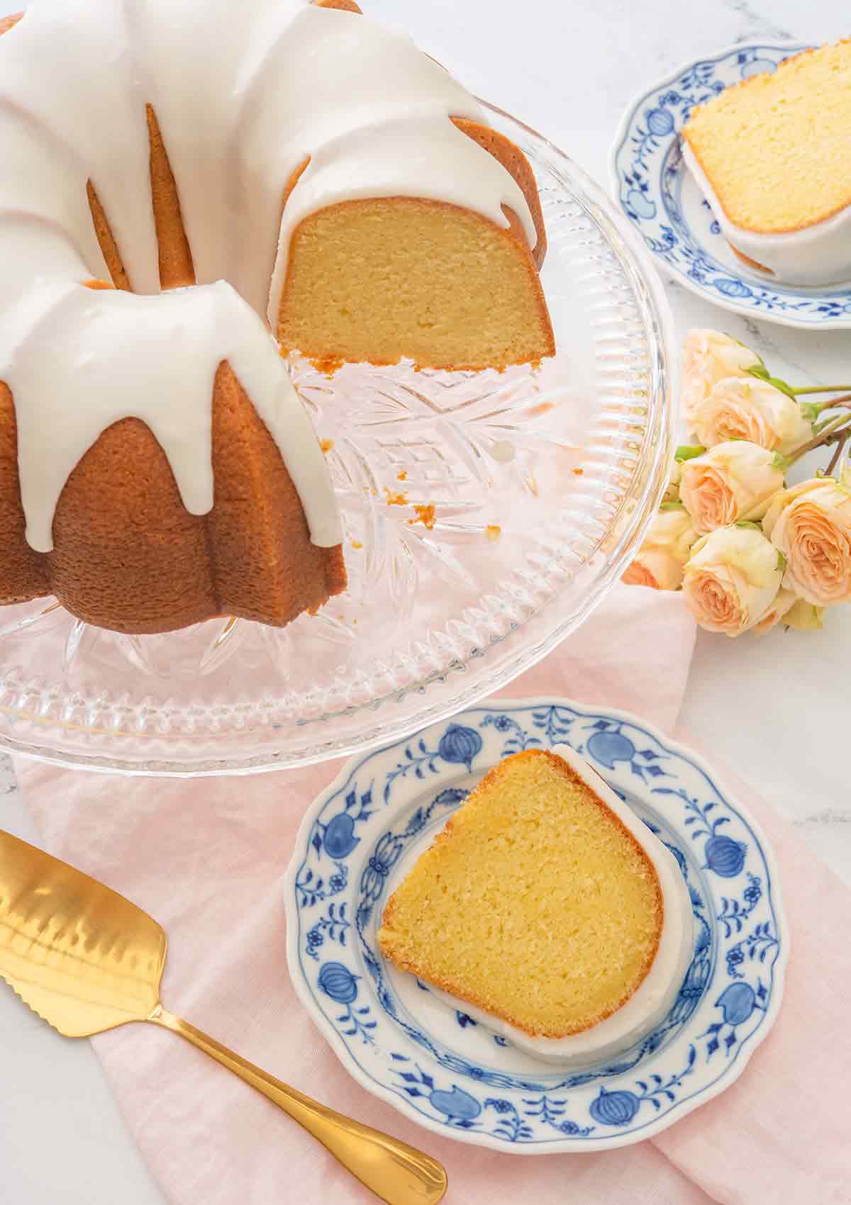 Overhead view of a vanilla Bundt cake with two slices cut out on their own small dessert plates.