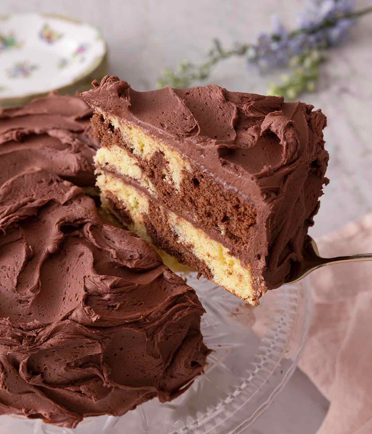 A slice of marble cake being lifted from the cake on a cake stand.
