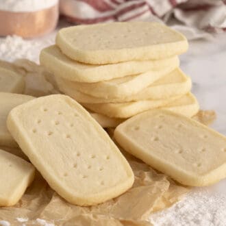 A group of delicious homemade shortbread cookies stacked on a marble surface with parchment paper.