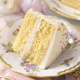 A moist and delicious slice of Vanilla Cake on a porcelain plate.