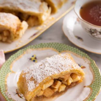 Pinterest graphic of a plate with a serving of apple strudel on it with the platter in the background, out of focus.