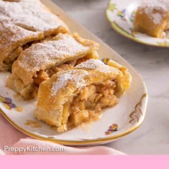 Pinterest graphic of a platter with a sliced apple strudel with a plate with a serving in the background.